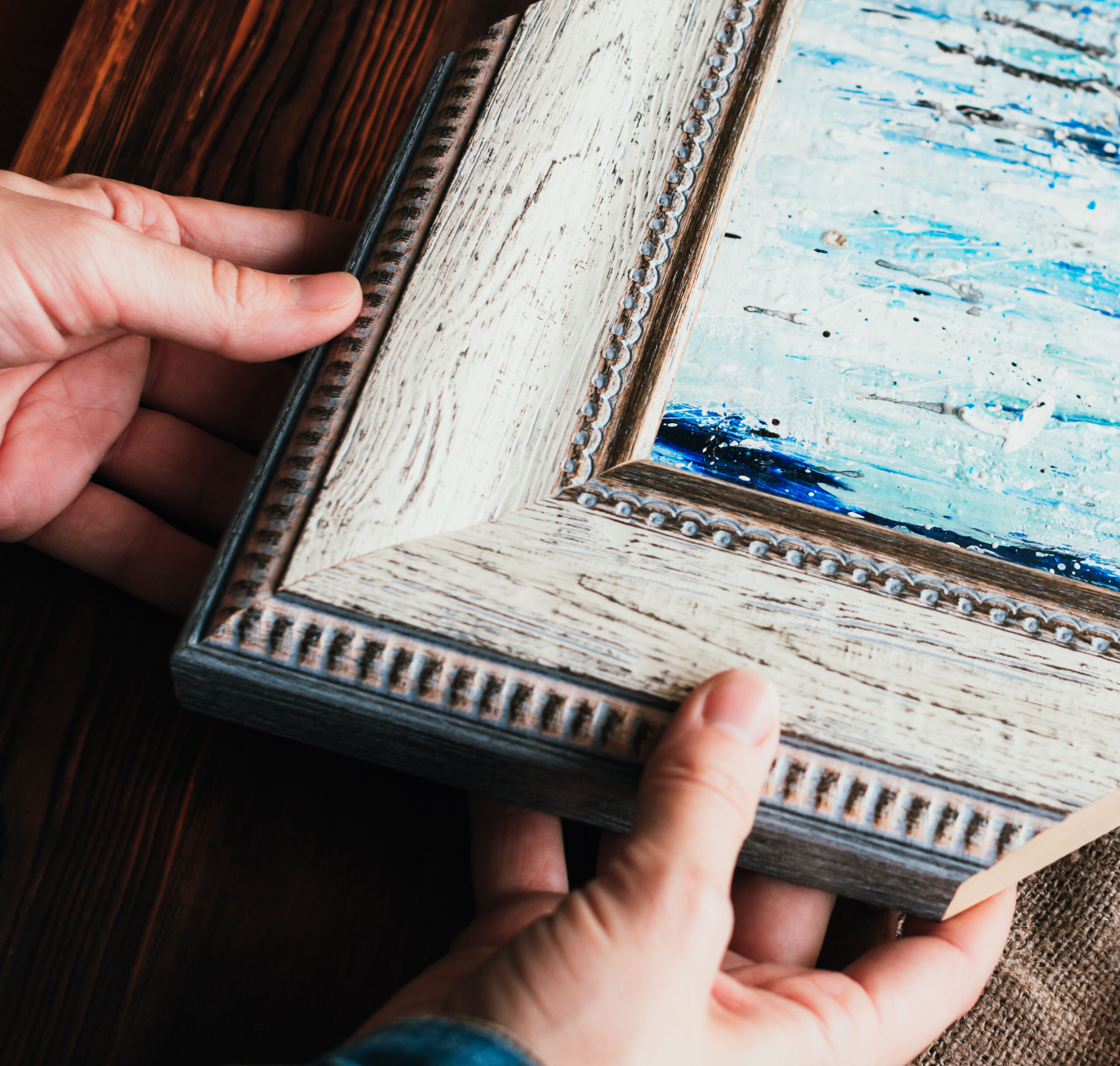 Choosing frame for a painting. Woman's hands and sample of wood