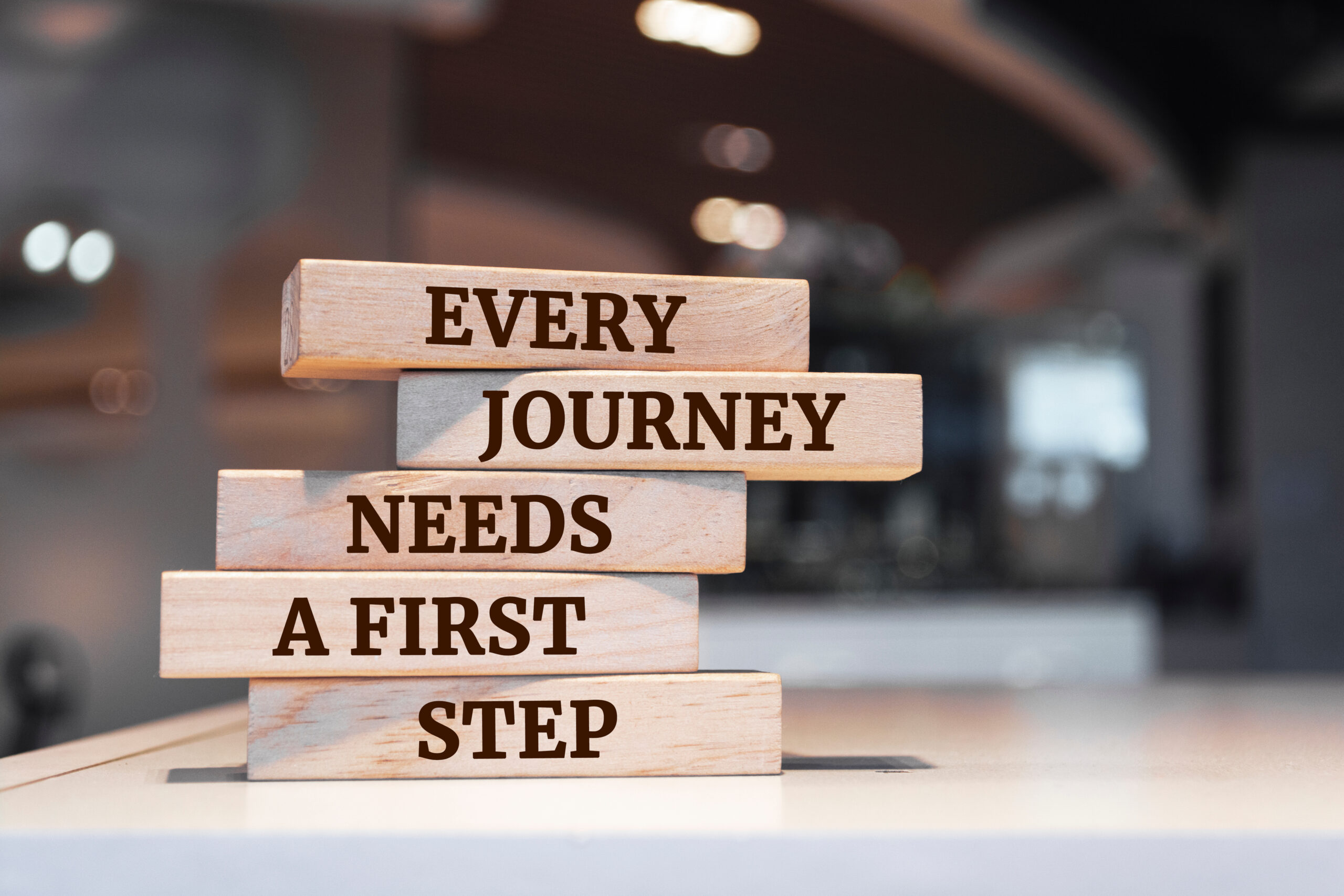 Wooden blocks with words 'Every journey needs a first step'.